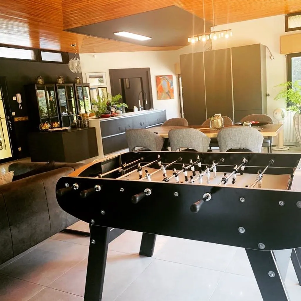 Salle de loisirs rénovée avec baby-foot et rangements sombres